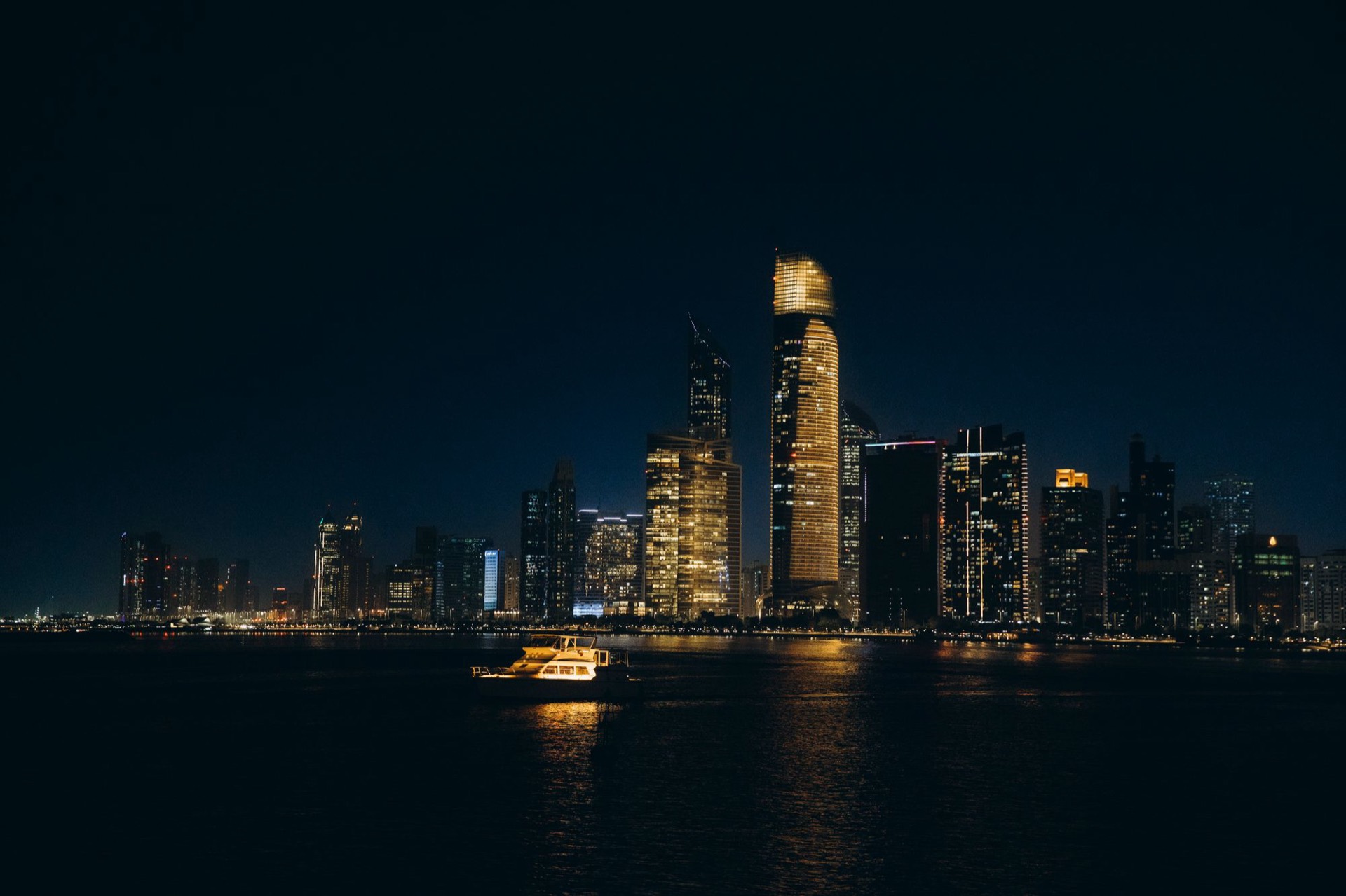 The Abu Dhabi skyline illuminated at night above the water